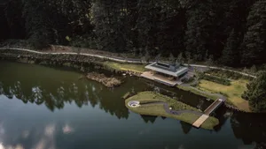 A modern waterfront house featuring concrete, glass, and wood materials.