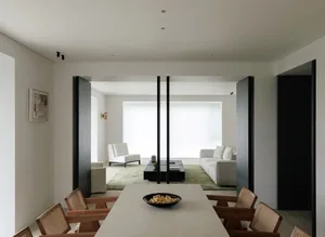 Minimalist interior design featuring a modern, neutral-toned living room with a sleek dining table and comfortable seating.