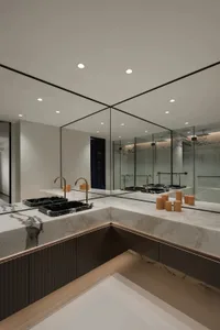 Modern bathroom with marble countertops, brass fixtures, and large mirrors.