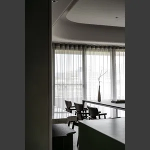 Modern dining room with neutral-tones furniture and transparent curtains.