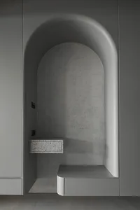 A modern interior design featuring a concrete niche with a floating shelf and seating area.