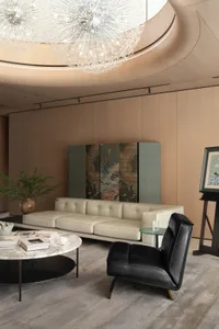 A modern living room featuring a white leather sofa, a black leather armchair, and a round marble coffee table.
