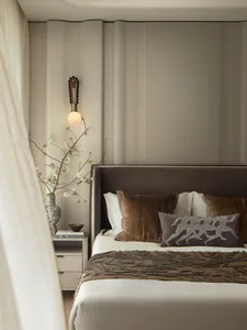Minimalist bedroom with a bed, pillows, and a vase of flowers on a side table.