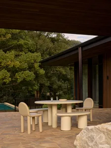 Modern patio furniture featuring round table and benches in sand color.