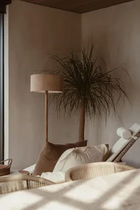 Modern minimalist living room featuring rattan furniture, linen cushions, and wooden blinds.