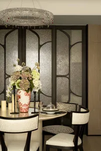 A modern dining room featuring glass walls, leather upholstered chairs, and metal accents.