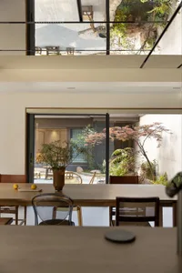 A modern dining room featuring wooden furniture and a serene outdoor view.
