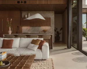 Modern living room with white sofa, wooden floor, marble kitchen counter, and large windows.