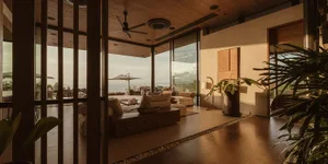 A modern living room featuring wooden furniture, concrete flooring, and textiles as key decor elements.