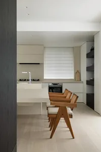 A modern minimalist kitchen with wooden elements and white countertops and appliances.
