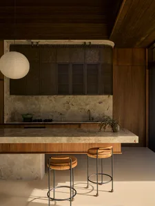 Modern residential kitchen featuring marble countertops and stools.