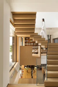 A modern residential library featuring wooden shelving and a glass staircase.