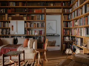 A minimalistic living room with bookshelves filled with books, a soft seating area, and wooden furniture.