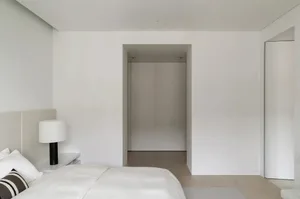 A minimalist bedroom with walls and bedding in neutral colors.