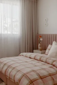 A modern pink and white bedroom with pastel textiles and soft lighting.