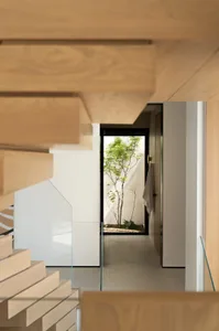A modern entrance hall featuring a glass door leading to a small garden with trees and plants.