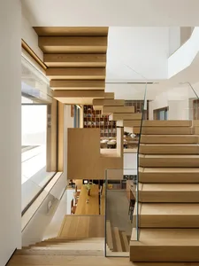 A modern interior design featuring a wooden staircase with a glass railing.