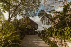 A modern landscape featuring natural elements and a pathway leading through a lush, green environment.
