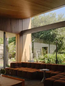 Modern living room featuring a comfortable couch, large glass window, and surrounding greenery.
