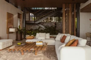 A modern living room with neutral-toned furniture and decor, featuring a cozy sectional, a glass coffee table, and various in