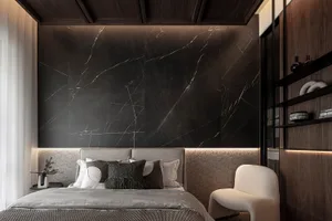 A modern bedroom featuring a black marble accent wall and a gray upholstered bed with geometric pillows.