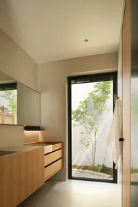 A modern minimalist bathroom with wooden elements and a view of a small garden through a window.