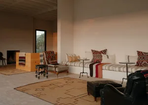 A minimalist living room with a low-slung couch adorned with patterned cushions and throw blankets, accompanied by a wooden t