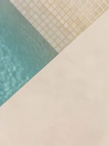A minimalist poolside area featuring concrete and terrazzo elements.