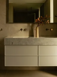 Modern bathroom featuring a marble countertop with a vase of dried leaves.