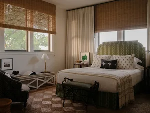 A modern bedroom featuring a bed with fabric bedding, a green upholstered headboard, and a cozy armchair.