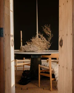 A modern dining room with a wooden table, ceramic vase, and chairs