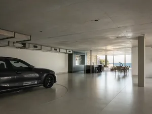A sleek, modern garage interior with a black vehicle parked in a concrete floor room.