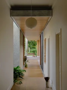 Modern hallway interior with concrete walls, bamboo ceiling, and wooden flooring.