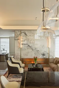 A modern living room with marble walls and a fireplace.