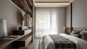 Modern bedroom featuring a bed with a plaid blanket, a wooden desk, and a walk-in closet with minimalist design and lighting.