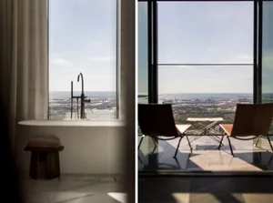 A view from a high-rise building showcasing a glass window overlooking a waterfront cityscape.