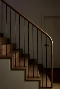 Modern minimalist staircase with wooden steps and black metal railings.
