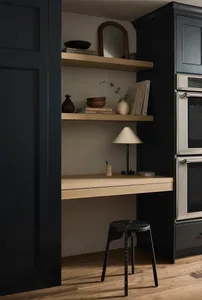A minimalist kitchen with floating shelves, a black stool, and a black cabinet with a double oven.
