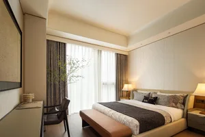 A modern bedroom with fabric finishes and a large window.
