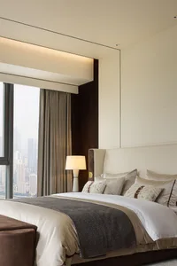 A modern bedroom with a white sofa, pillows, and a lamp.