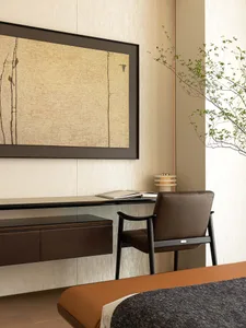 Minimalist bedroom featuring a modern floating desk made of wood, with an open book and a plant in the corner.