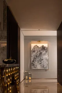 A modern corridor featuring marble and glass materials with a mountain landscape painting on the wall and lanterns on the flo