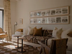 A modern living room with a white sectional sofa adorned with various cushions and blankets, accompanied by a side table with