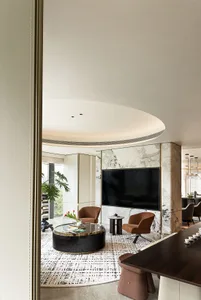 A modern living room with marble and concrete elements, featuring a round coffee table and brown armchairs.