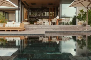 A modern residential patio featuring a pool, furniture, and outdoor living space.