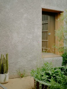 Modern residential house exterior with stucco walls and wooden accents.
