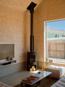 A minimalist living room with wood walls and a large window overlooking mountains.