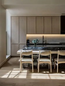 A modern minimalist kitchen with marble countertops and white oak cabinets.