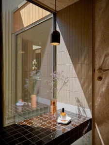 A modern bathroom featuring black ceramic tiles, pendant lighting, and decorative elements.