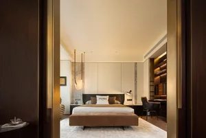 A modern bedroom with wooden furnishings, marble accents, and a upholstered bed with a Fendi Roma pillow.